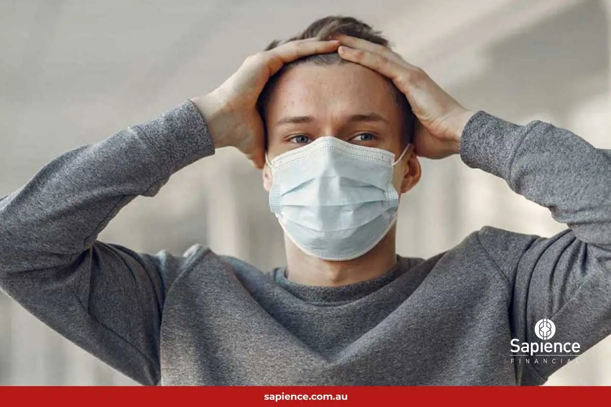male with surgical face mask holding his head