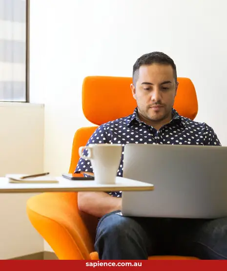 person sitting on orange chair working on laptop computer