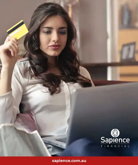 person sitting in front of laptop computer thinking about using a credit card for a purchase