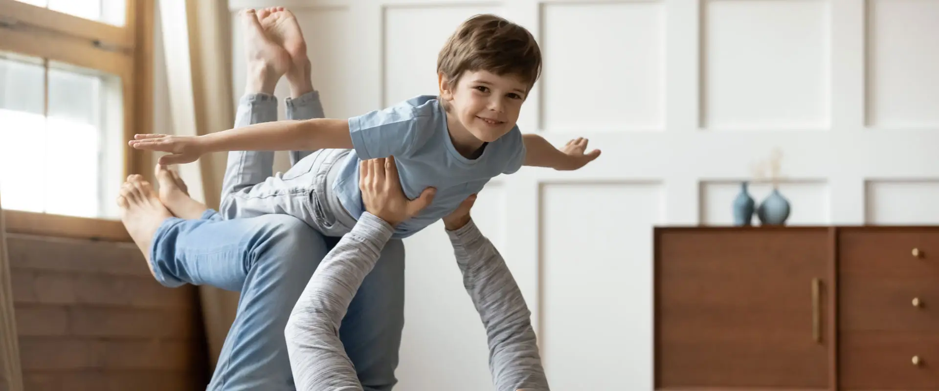 father playing with his young son who pretends to fly