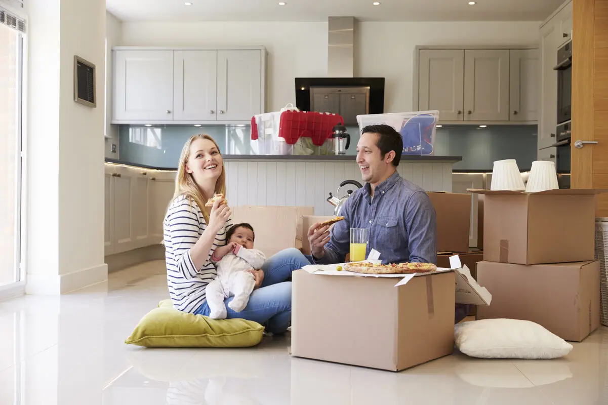 young couple and their child sitting on the floor in their first home